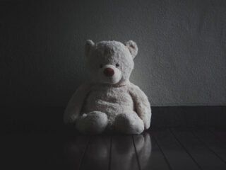 child's teddy bear sitting in darkness