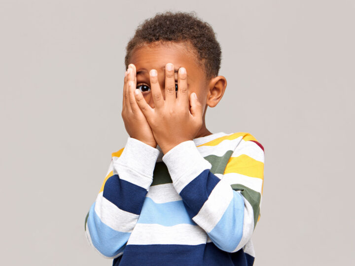 shy child with hands over his face