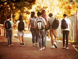 group of teens walking down a sidewalk