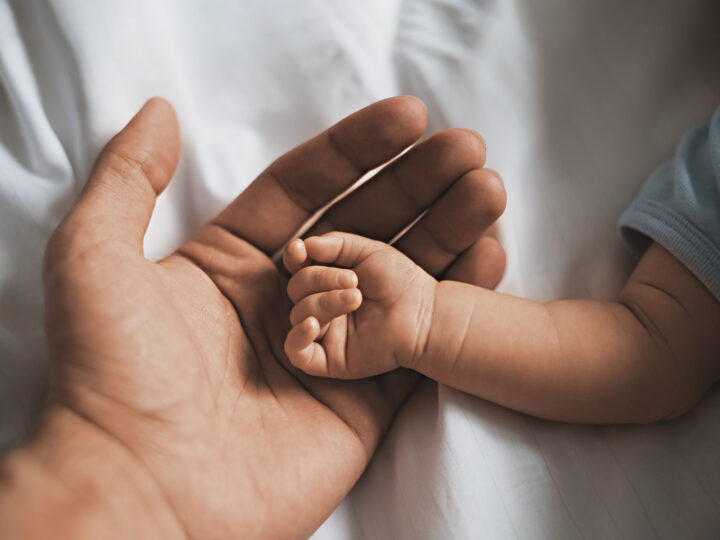 Close up small hands of baby is lying in men of his father hands, concept of caring, fatherhood